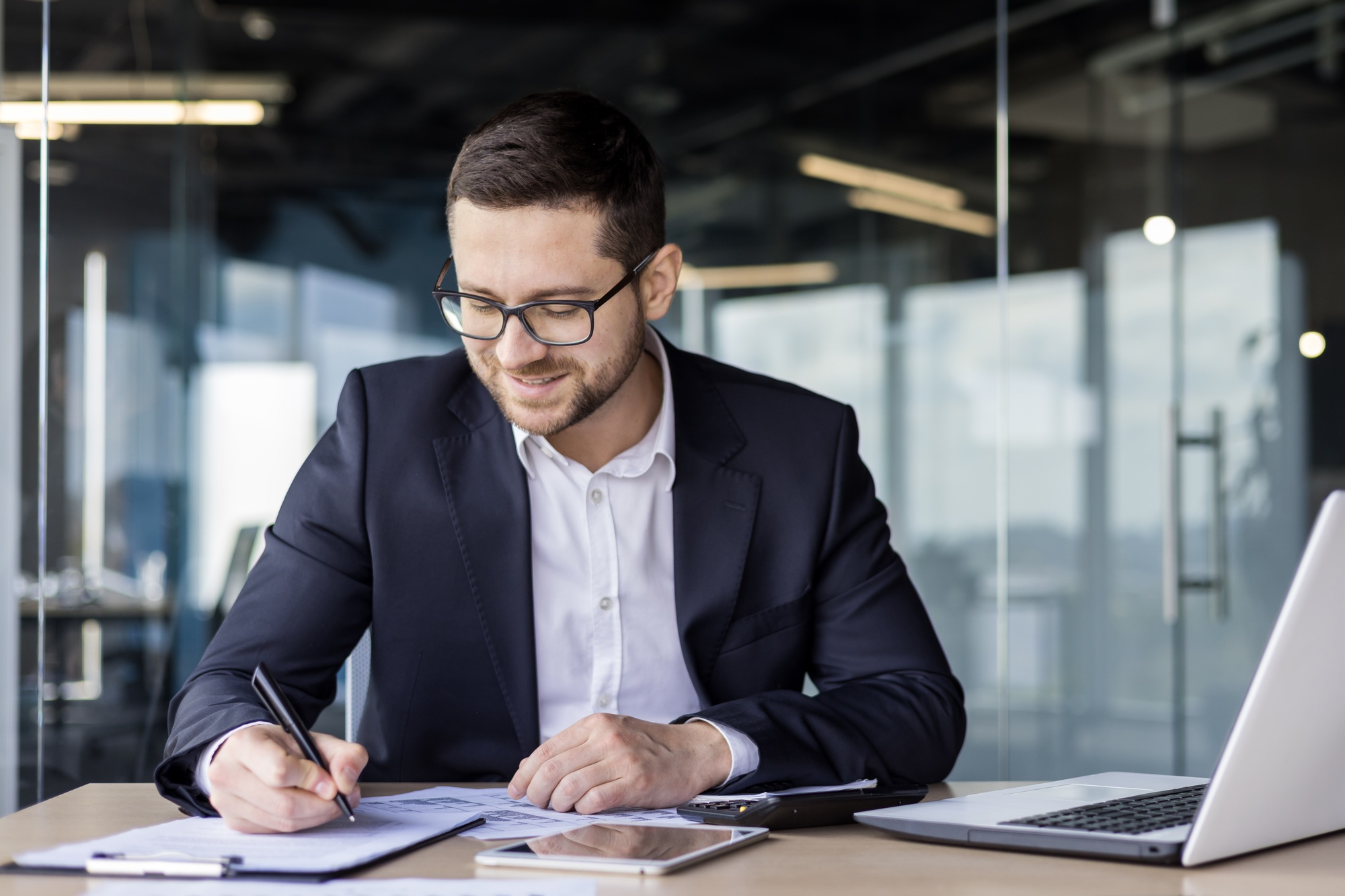 Young businessman working in the office at the workplace with documents, signing an agreement