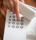 Female hand holding telephone receiver dialing a phone number