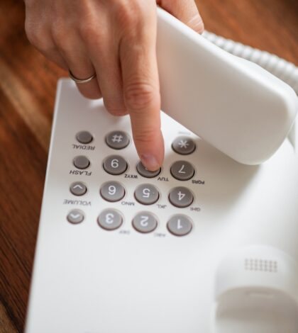 Female hand holding telephone receiver dialing a phone number