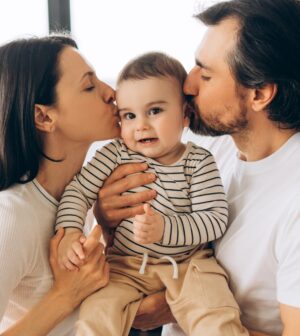 Happy parents kissing their baby son at home