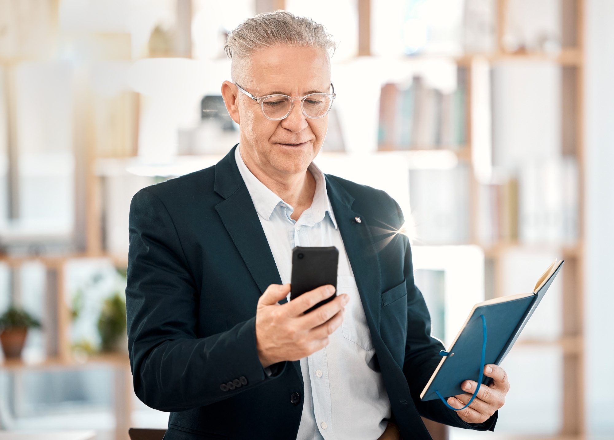 Notebook, phone and senior business man in office for client contact, reading directory and plannin