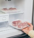 cropped view of man taking out frozen meat from freezer