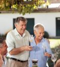 Happy senior couple with family having lunch together outside
