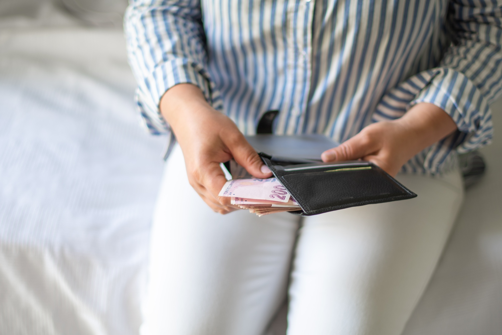 Leather wallet with money in the hands of a woman who takes out a pack of 200 Turkish lira bills