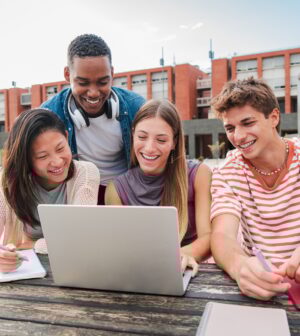 Teamwork of teenage students using a laptop to prepare a exam. Group of classmates learning together