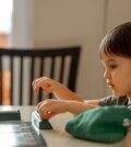 The child sits at the table and plays a board game. Playing words