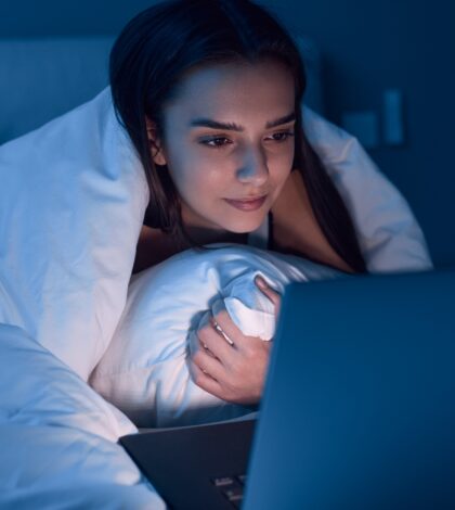 Woman watching movie in bed at night